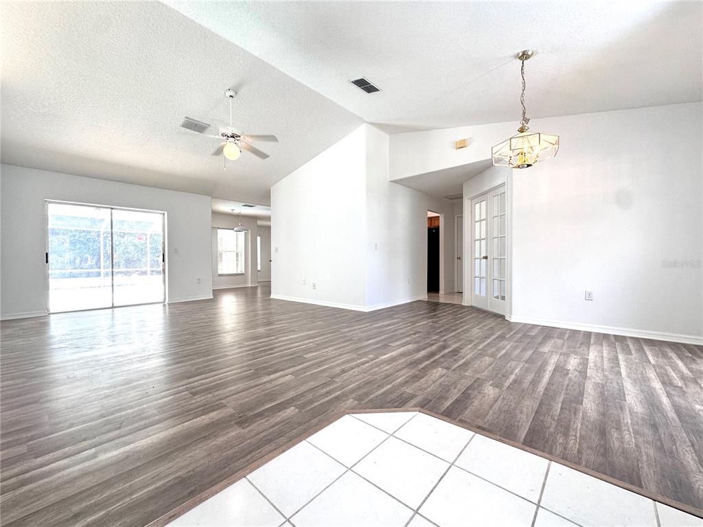 An open-concept living area features wood-look flooring, vaulted ceilings, a ceiling fan, and sliding doors — 29439 SCHINNECOCK HILLS LANE, SAN ANTONIO, FL