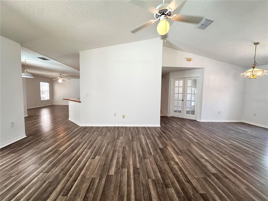 An open-concept living area features vaulted ceilings, wood-look flooring, and a central white wall — 29439 SCHINNECOCK HILLS LANE, SAN ANTONIO, FL