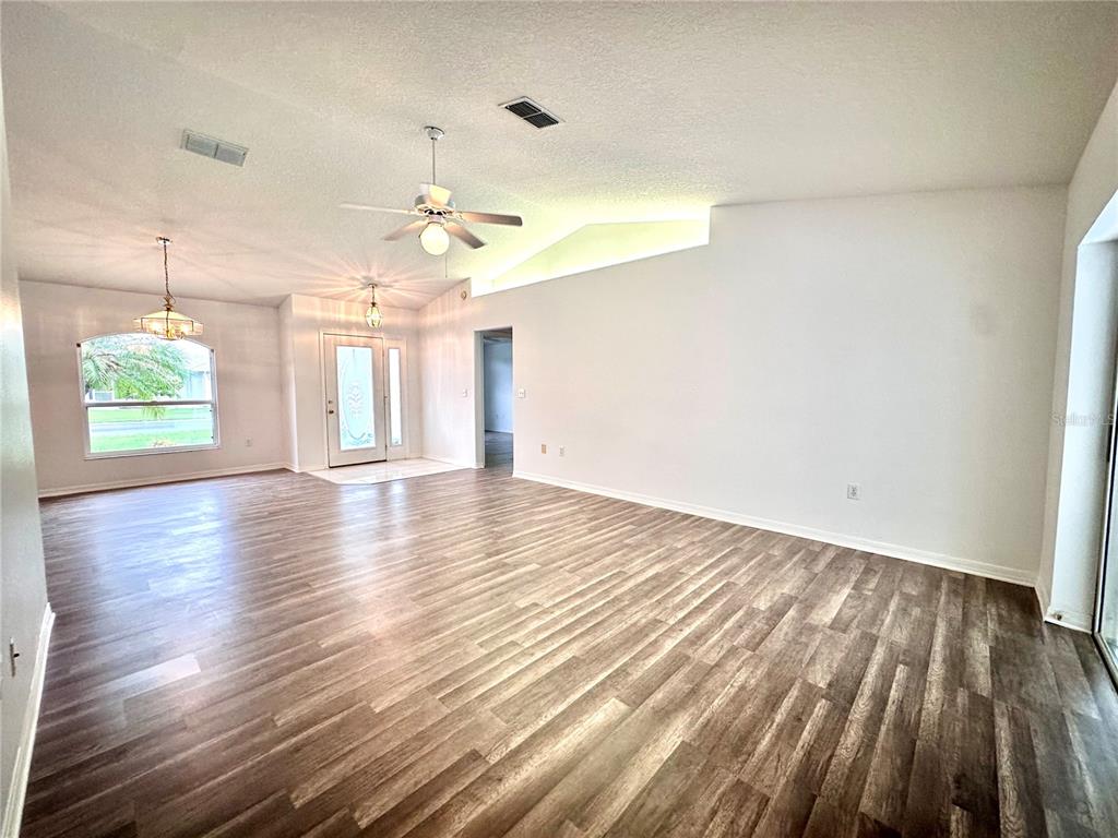 A spacious living room features wood-look flooring, a ceiling fan, and a vaulted ceiling — 29439 SCHINNECOCK HILLS LANE, SAN ANTONIO, FL