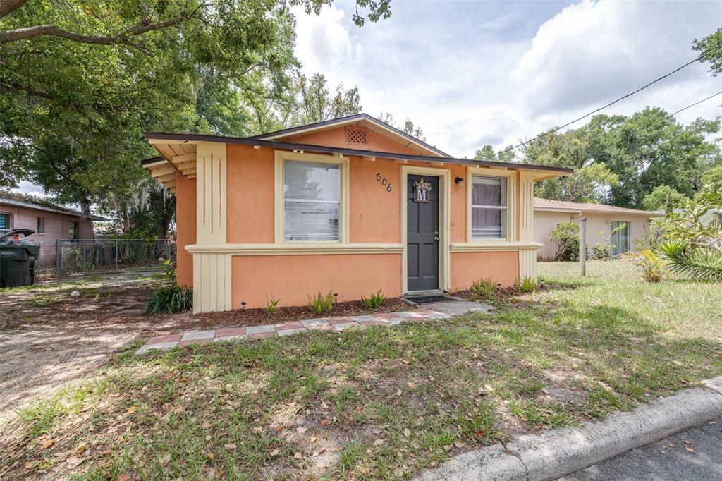 A small, orange, single-story house with a dark front door and a tiled walkway — 506 WHITEHURST STREET, LAKELAND, FL