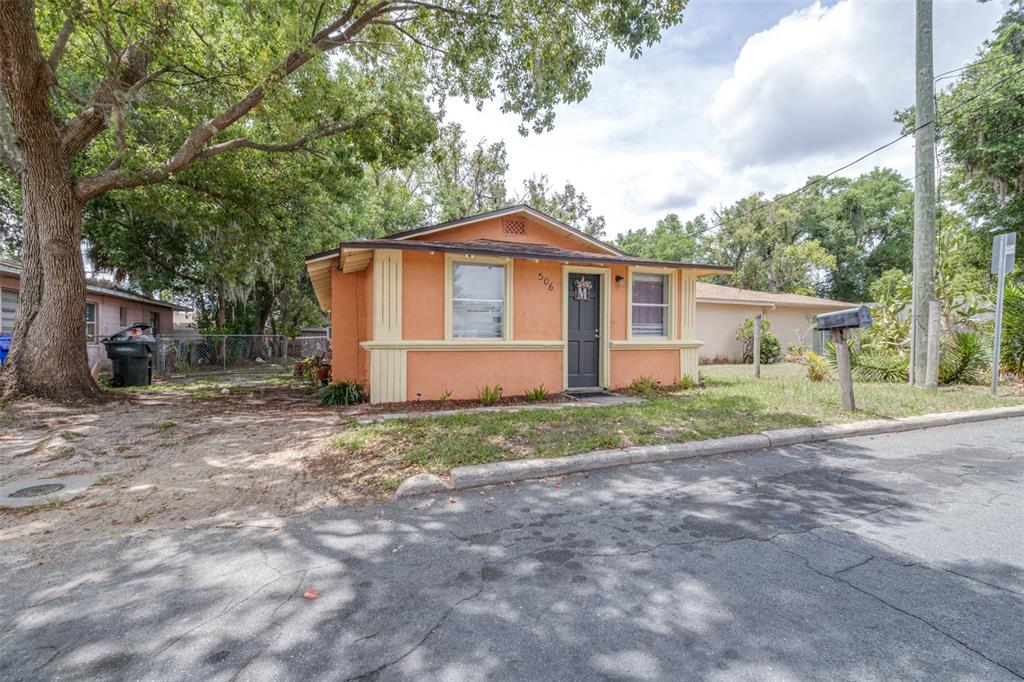 A small, orange, single-story house with a dark front door sits on a grassy lot — 506 WHITEHURST STREET, LAKELAND, FL