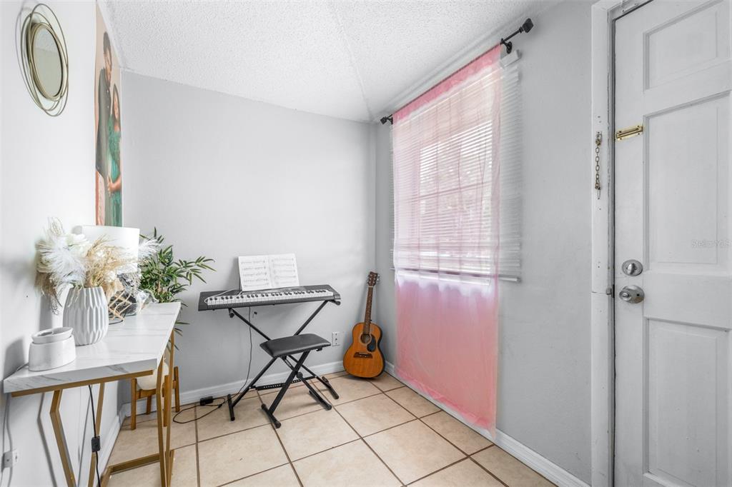 A room with tile flooring, a keyboard on a stand, a guitar, and a white desk — 506 WHITEHURST STREET, LAKELAND, FL