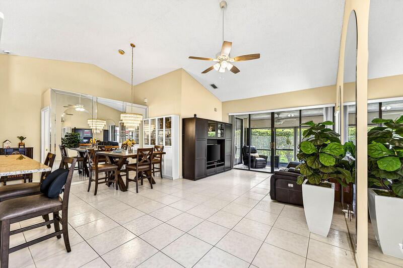 A bright, open-concept living and dining area features vaulted ceilings, tile flooring, and mirrored walls — 7888 Lexington Club Boulevard # B, Delray Beach FL 33446, DELRAY BEACH, FL