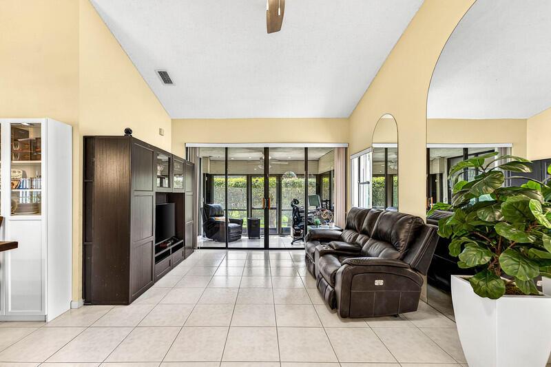 A living room features a dark entertainment center, a leather sofa, and sliding glass doors — 7888 Lexington Club Boulevard # B, Delray Beach FL 33446, DELRAY BEACH, FL