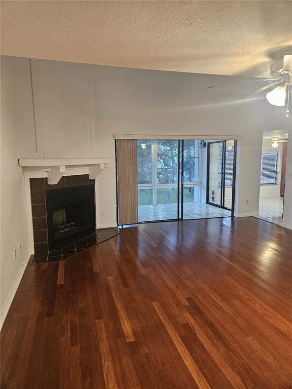 A living room with hardwood floors, a corner fireplace, and sliding glass doors to a patio — 4723 PURITAN CIRCLE UNIT 624, TAMPA, FL