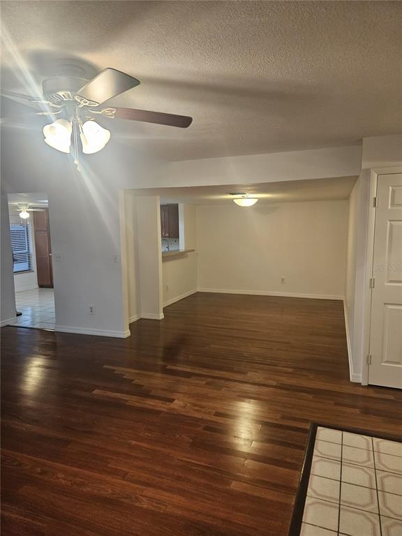 An open-concept living area features dark wood flooring, a ceiling fan, and a kitchen pass-through — 4723 PURITAN CIRCLE UNIT 624, TAMPA, FL