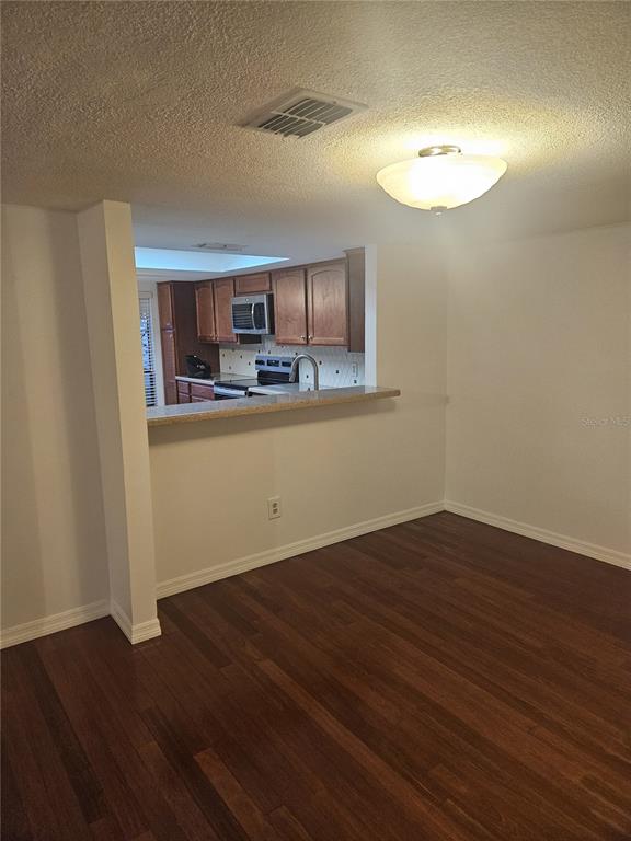 A dining area with wood flooring looks into a kitchen with wood cabinets and countertops — 4723 PURITAN CIRCLE UNIT 624, TAMPA, FL