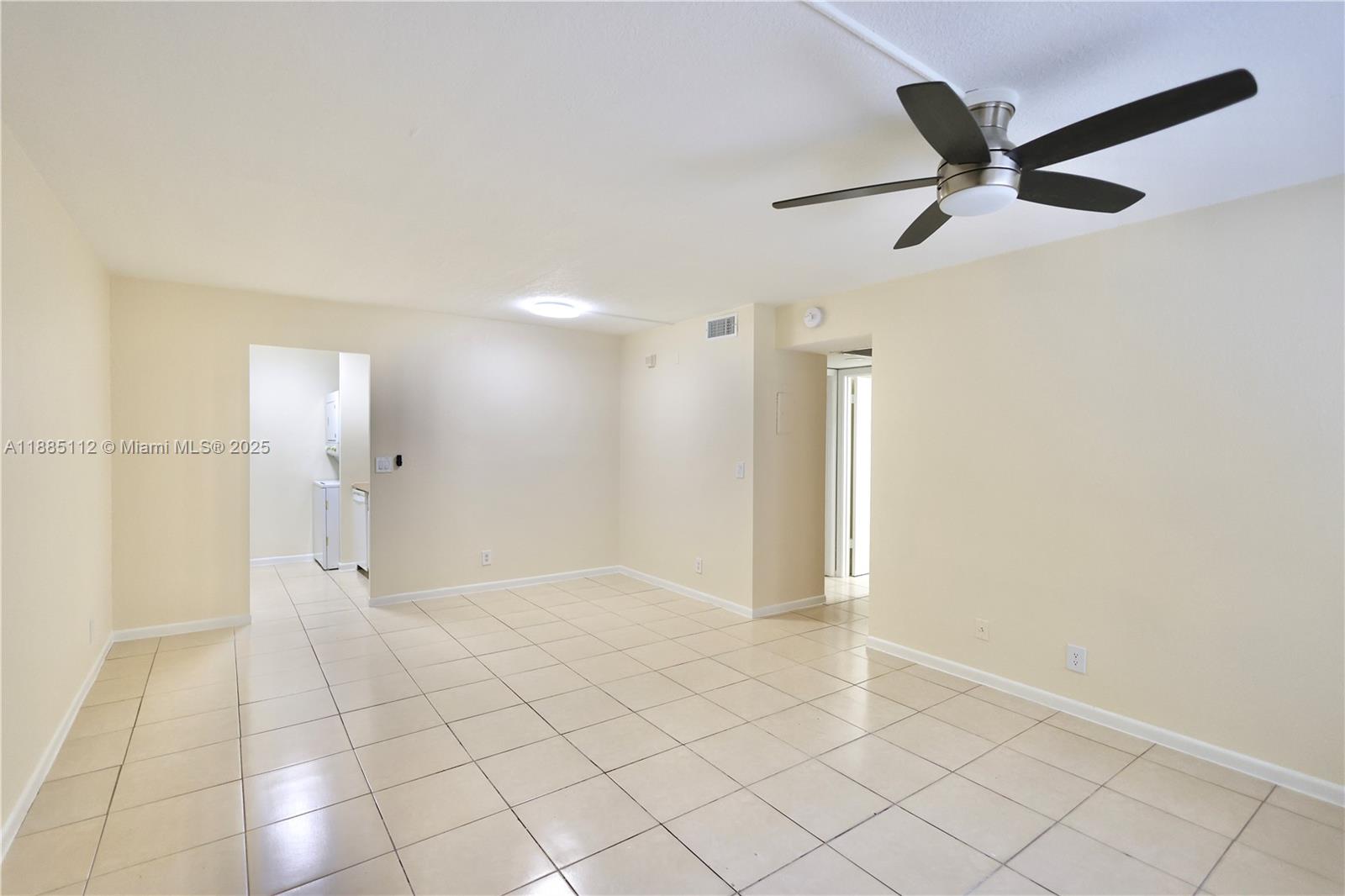 An empty room features beige tile flooring, cream-colored walls, and a ceiling fan — 10016 Twin Lakes Dr # C, Coral Springs FL 33071, CORAL SPRINGS, FL