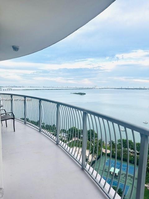 A balcony with a metal railing overlooks a large body of water and tennis courts — 1750 N Bayshore Dr # 2302, Miami FL 33132, MIAMI, FL