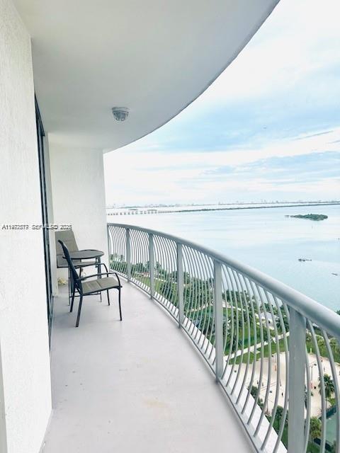 A curved balcony with metal railings overlooks a bay and a park below — 1750 N Bayshore Dr # 2302, Miami FL 33132, MIAMI, FL