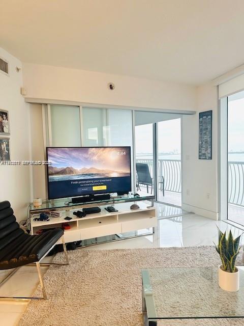 A living room features a television on a white stand, a chair, and balcony views — 1750 N Bayshore Dr # 2302, Miami FL 33132, MIAMI, FL