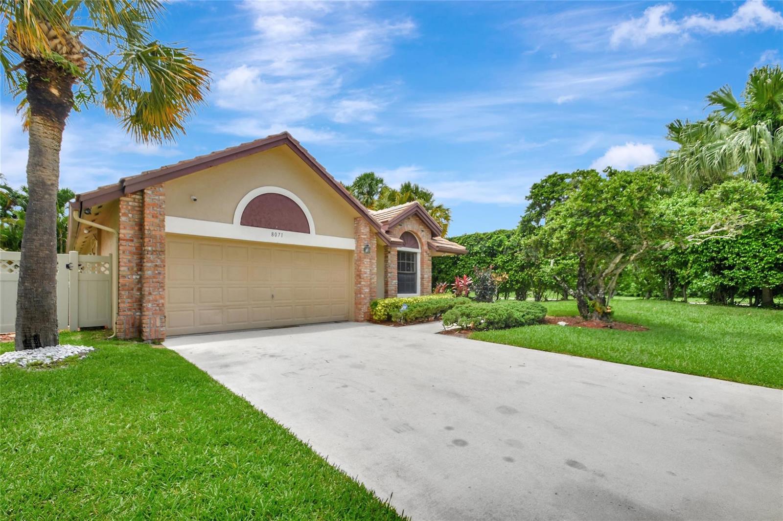 A single-story house with a tan stucco facade, brick accents, and a two-car garage — 8071 Popash Court, Boynton Beach FL 33472, BOYNTON BEACH, FL