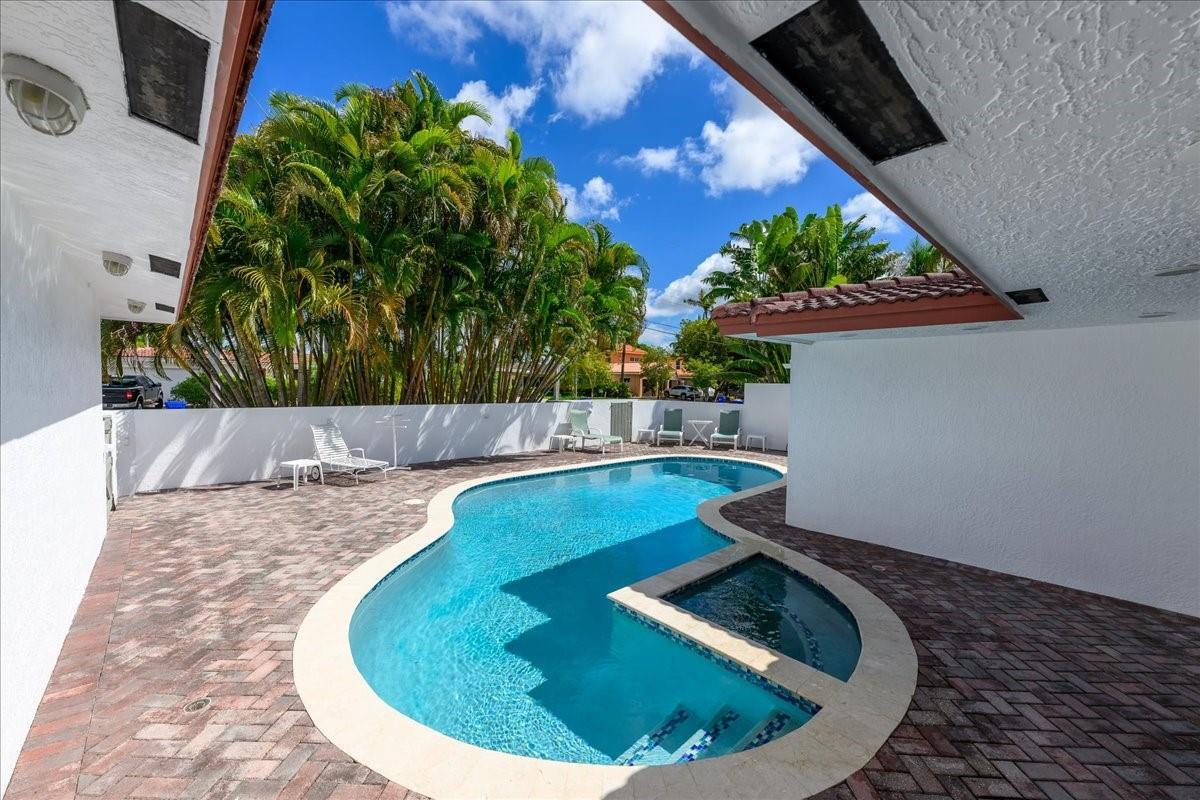 A kidney-shaped swimming pool with an attached spa sits on a brick-paved patio — 200 SE 11th Street, Pompano Beach FL 33060, POMPANO BEACH, FL