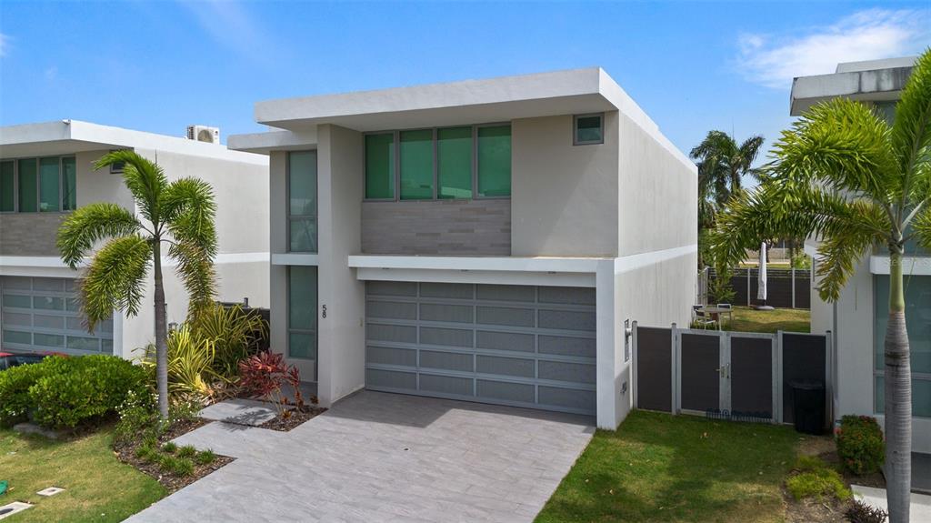 A modern two-story house features a gray garage, flat roof, and green-tinted windows — Riviera 58 CENTRAL PARK STREET, BAYAMON, PR