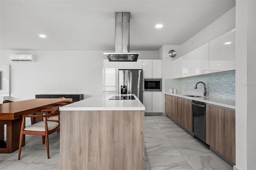 A modern kitchen features a wood-paneled island, white cabinetry, stainless steel appliances, and tile flooring — Riviera 58 CENTRAL PARK STREET, BAYAMON, PR