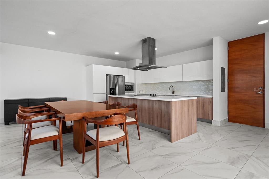 A modern kitchen features a wooden island, white cabinetry, and an adjacent dining area — Riviera 58 CENTRAL PARK STREET, BAYAMON, PR