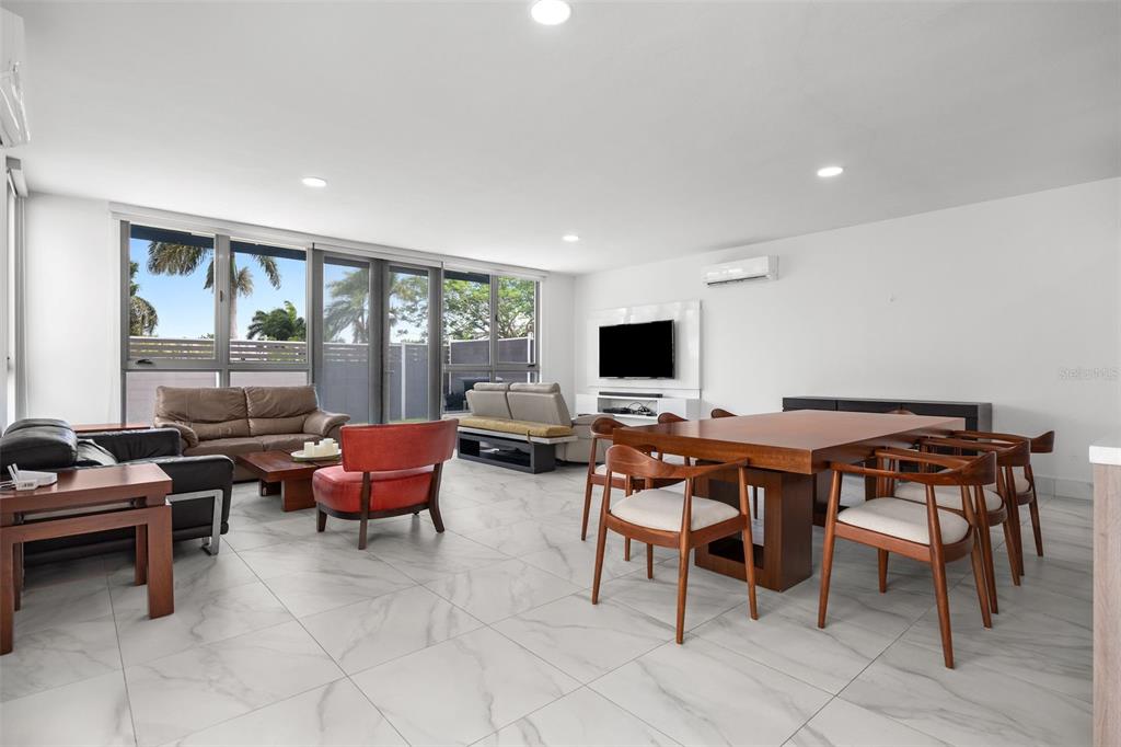 A bright living and dining area with white tile floors, modern furniture, and large windows — Riviera 58 CENTRAL PARK STREET, BAYAMON, PR