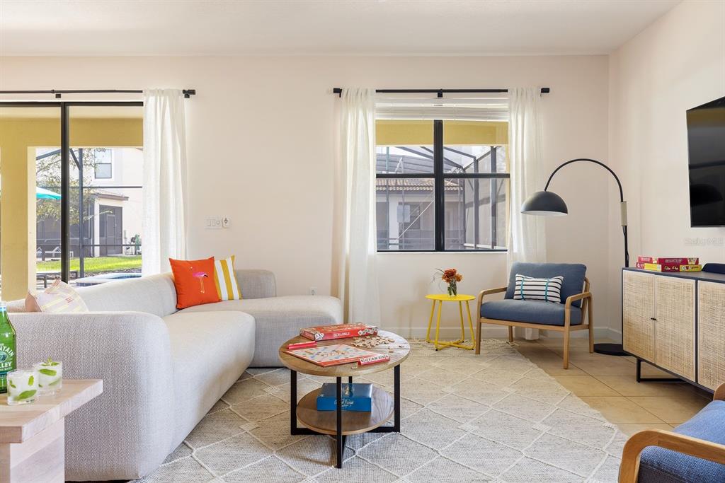A living room features a light-colored sectional sofa, a round coffee table, and blue armchairs — 9034 SHADOW MOUNTAIN STREET, DAVENPORT, FL