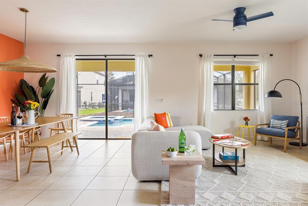 A bright living and dining area features tile floors, a pool view, and modern furniture — 9034 SHADOW MOUNTAIN STREET, DAVENPORT, FL