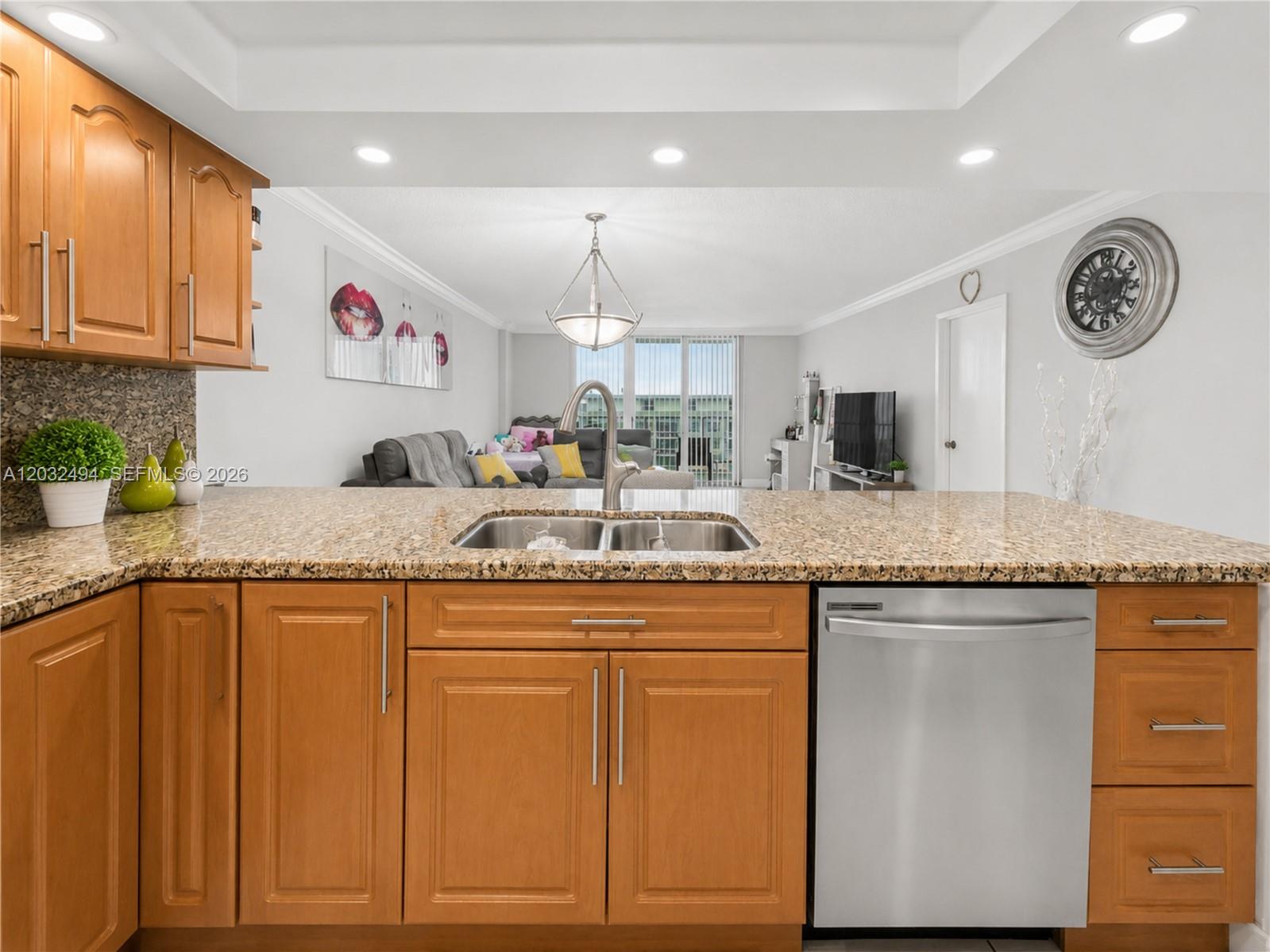 A kitchen island with a stainless steel sink and dishwasher faces an open-concept living area — 5701 Collins Ave # 1711, Miami Beach FL 33140, MIAMI BEACH, FL