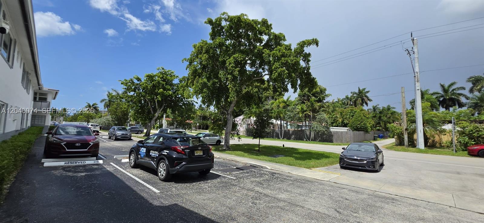 A parking lot with several cars sits in front of a building and trees — 1431 S 14th Ave # 217, Hollywood FL 33020, HOLLYWOOD, FL