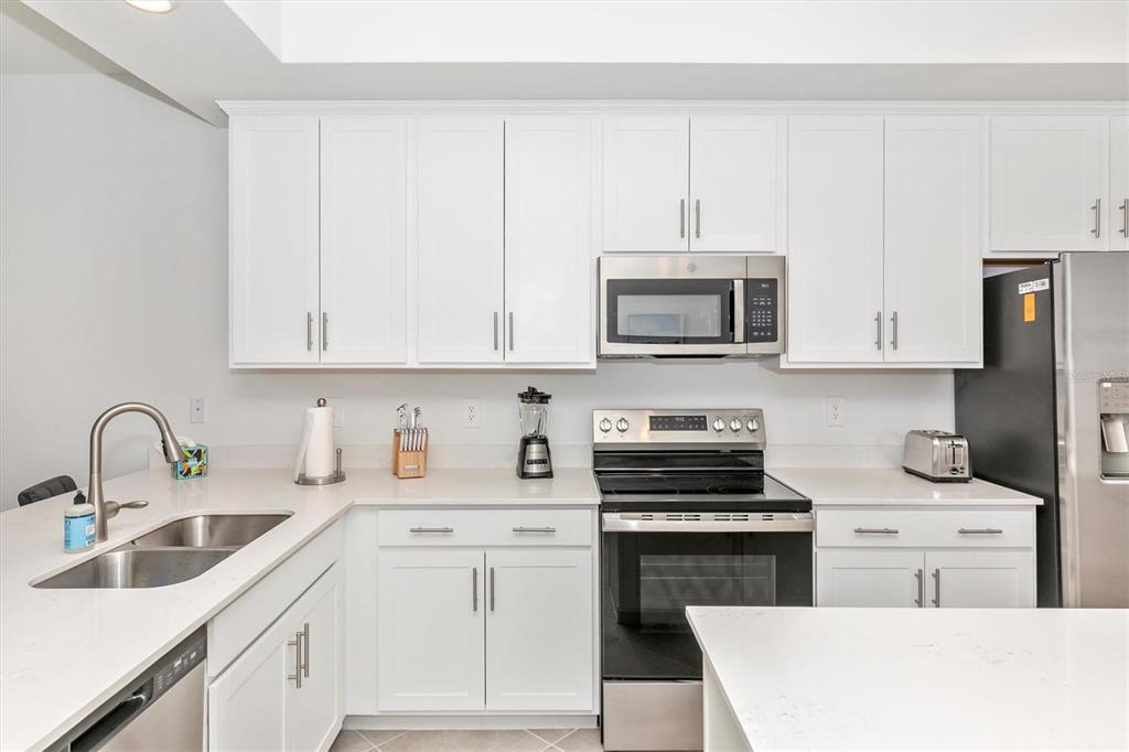 A kitchen features white cabinets, stainless steel appliances, and light-colored countertops — 17565 OPAL SAND DRIVE UNIT 305, VENICE, FL