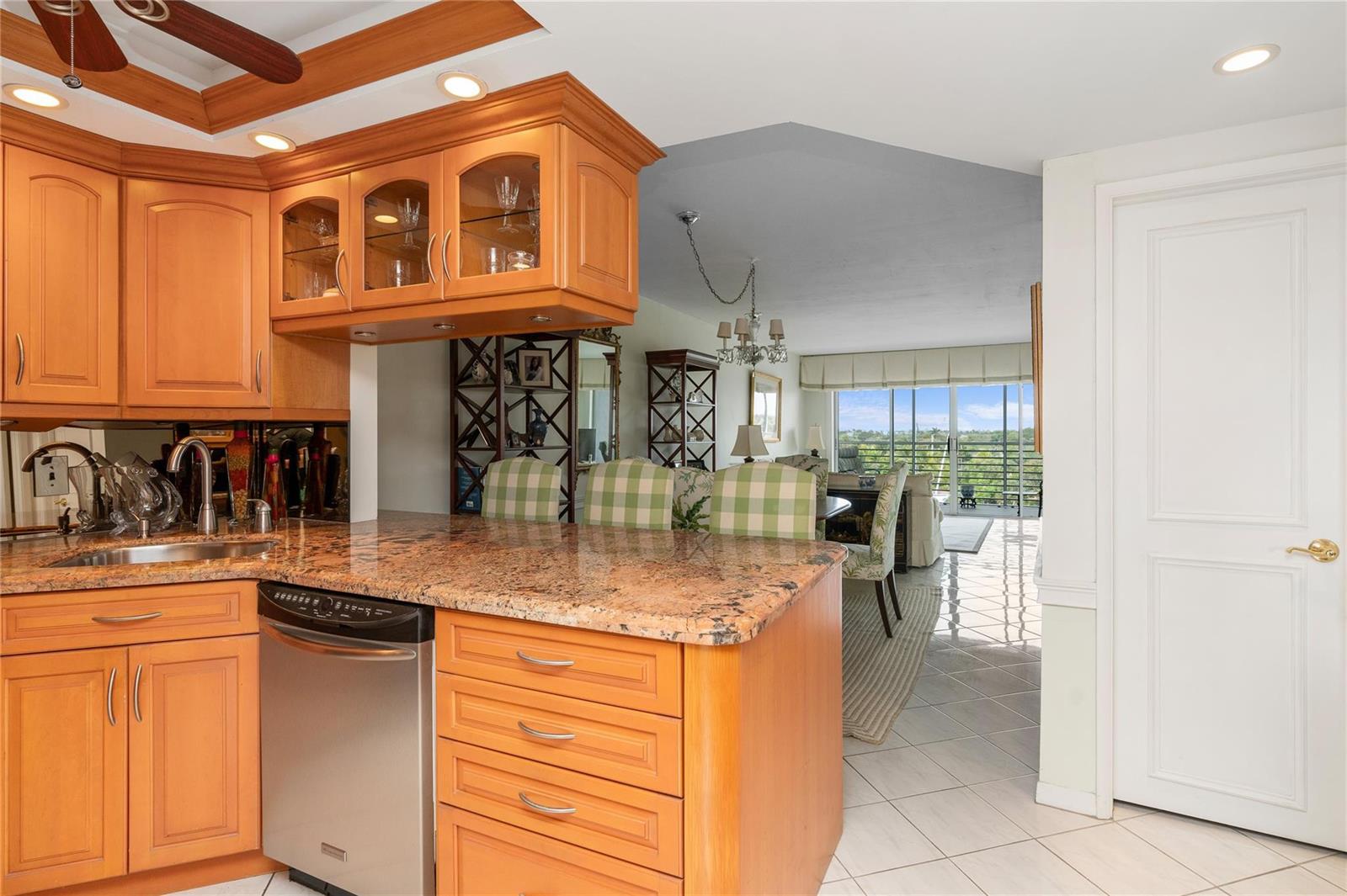 A kitchen with wood cabinets and granite countertops overlooks a dining area with balcony views — 2731 NE 14th Street Causeway # 637, Pompano Beach FL 33062, POMPANO BEACH, FL