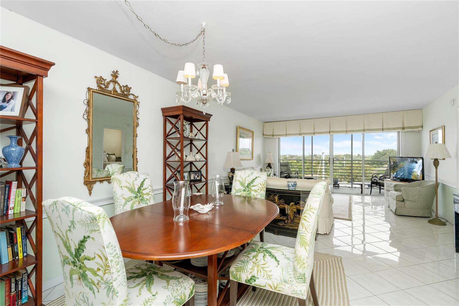 A dining area with a wooden table and floral chairs sits before a bright living room — 2731 NE 14th Street Causeway # 637, Pompano Beach FL 33062, POMPANO BEACH, FL