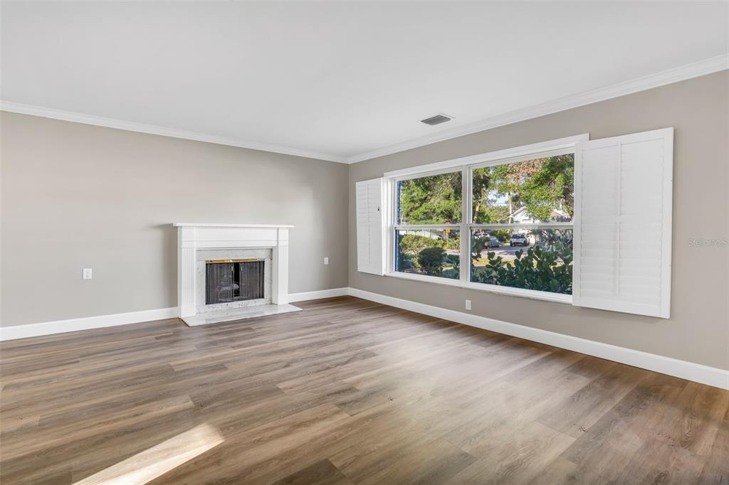 A living room with light gray walls, wood-look flooring, a white fireplace, and large windows — 216 S SHORE CREST DRIVE, TAMPA, FL