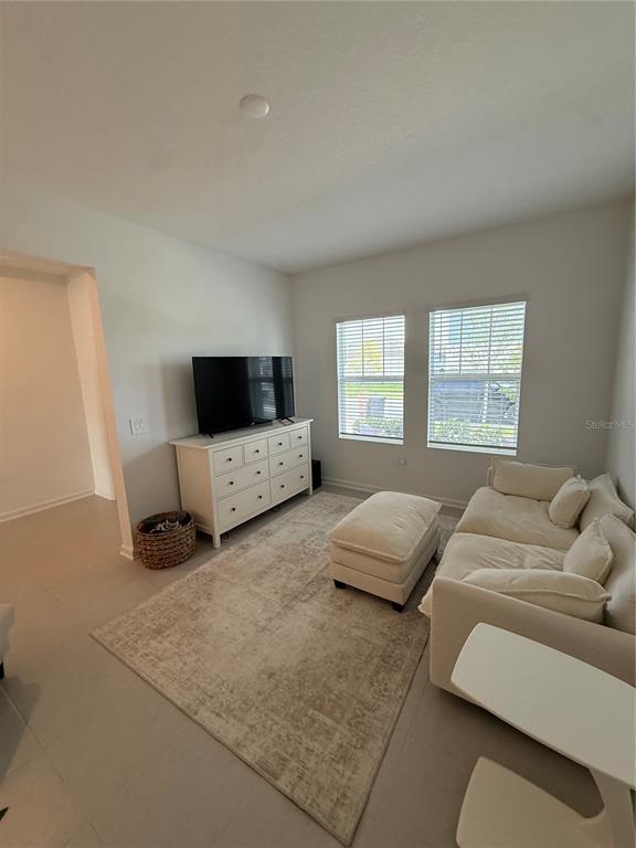 A living room features a white dresser, a television, a sofa with an ottoman, and windows — 629 TERRAPIN DRIVE, DEBARY, FL