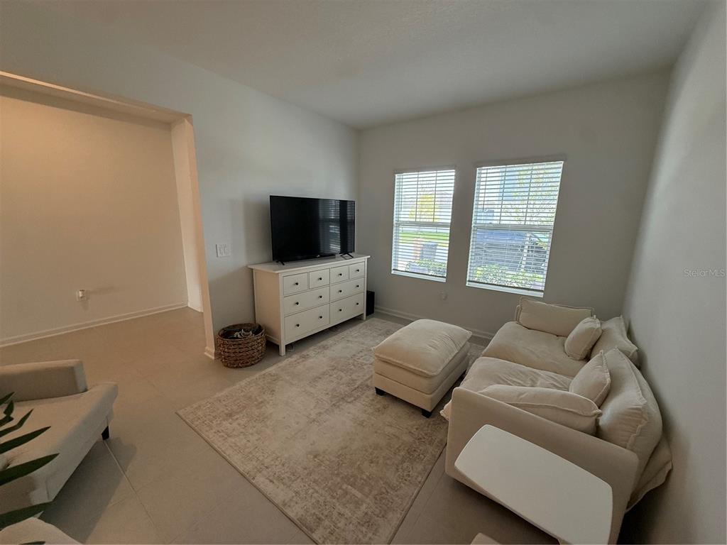 A living room features a white dresser with a television, a sofa, and an ottoman — 629 TERRAPIN DRIVE, DEBARY, FL
