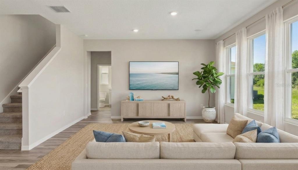 A living room features a sectional sofa, a television, a console table, and large windows — 32744 WEATHERED OAK DRIVE, WESLEY CHAPEL, FL