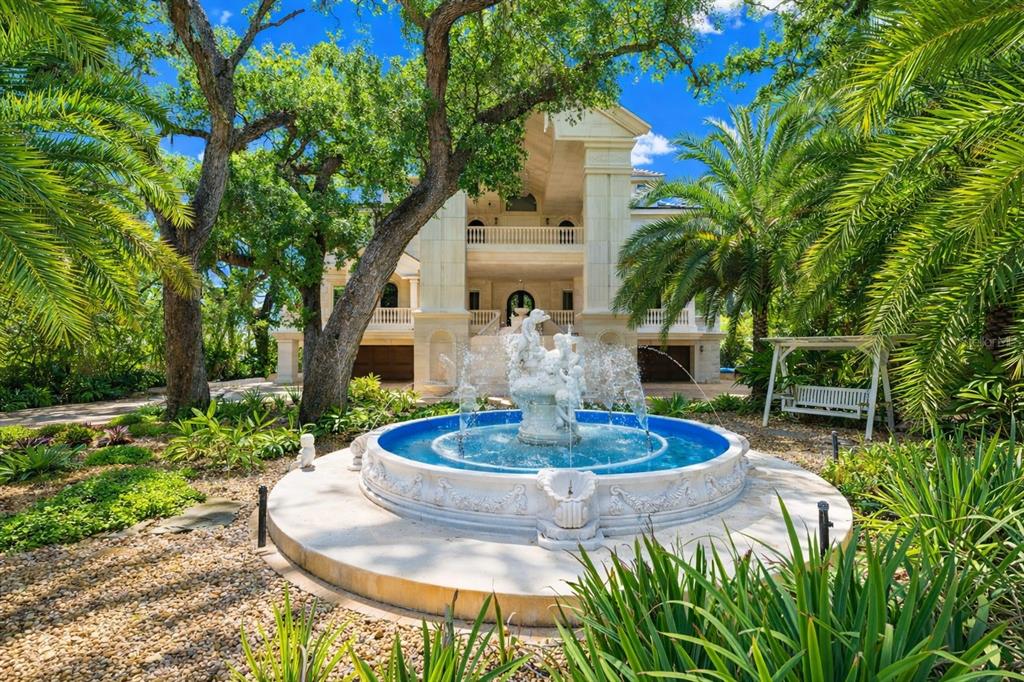 A large stone fountain sits in the foreground of a multi-story mansion with palm trees — 2000 PARK STREET N, ST PETERSBURG, FL