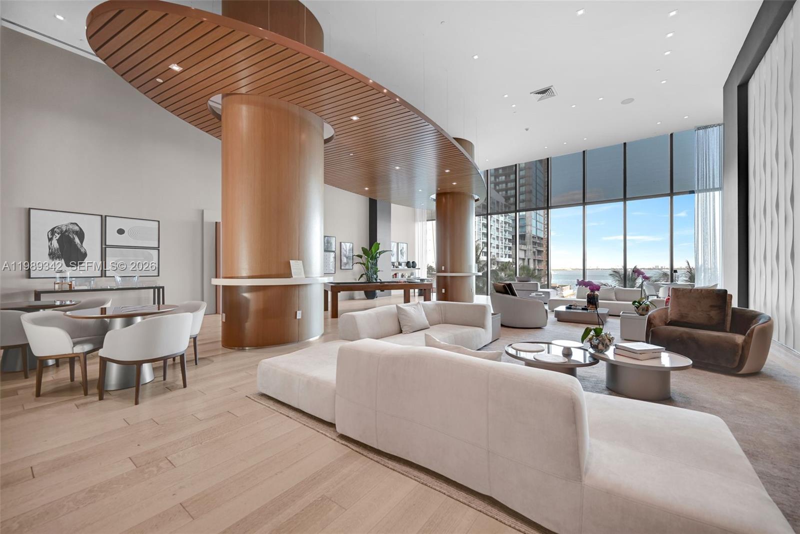 A modern, open-concept living area features a wooden ceiling feature, large windows, and neutral furniture — 460 NE 28th St # 601, Miami FL 33137, MIAMI, FL