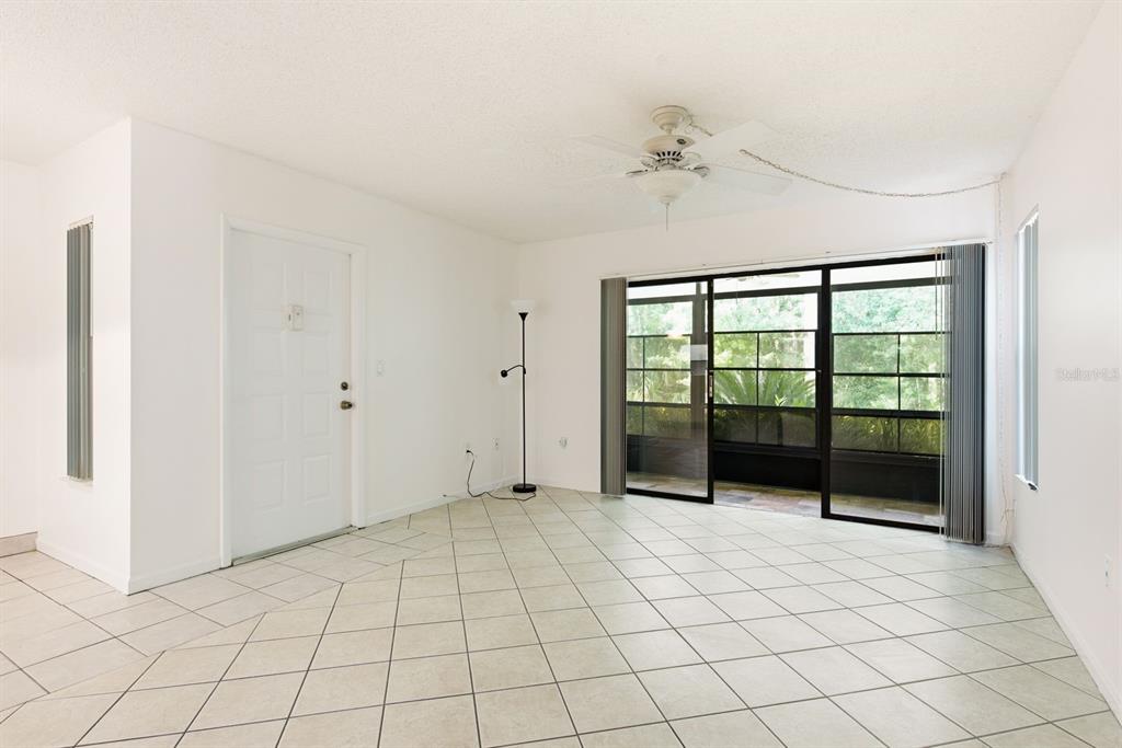 An empty room with white walls, tile flooring, a ceiling fan, and sliding glass doors — 1204 PINE RIDGE CIRCLE W UNIT C1, TARPON SPRINGS, FL