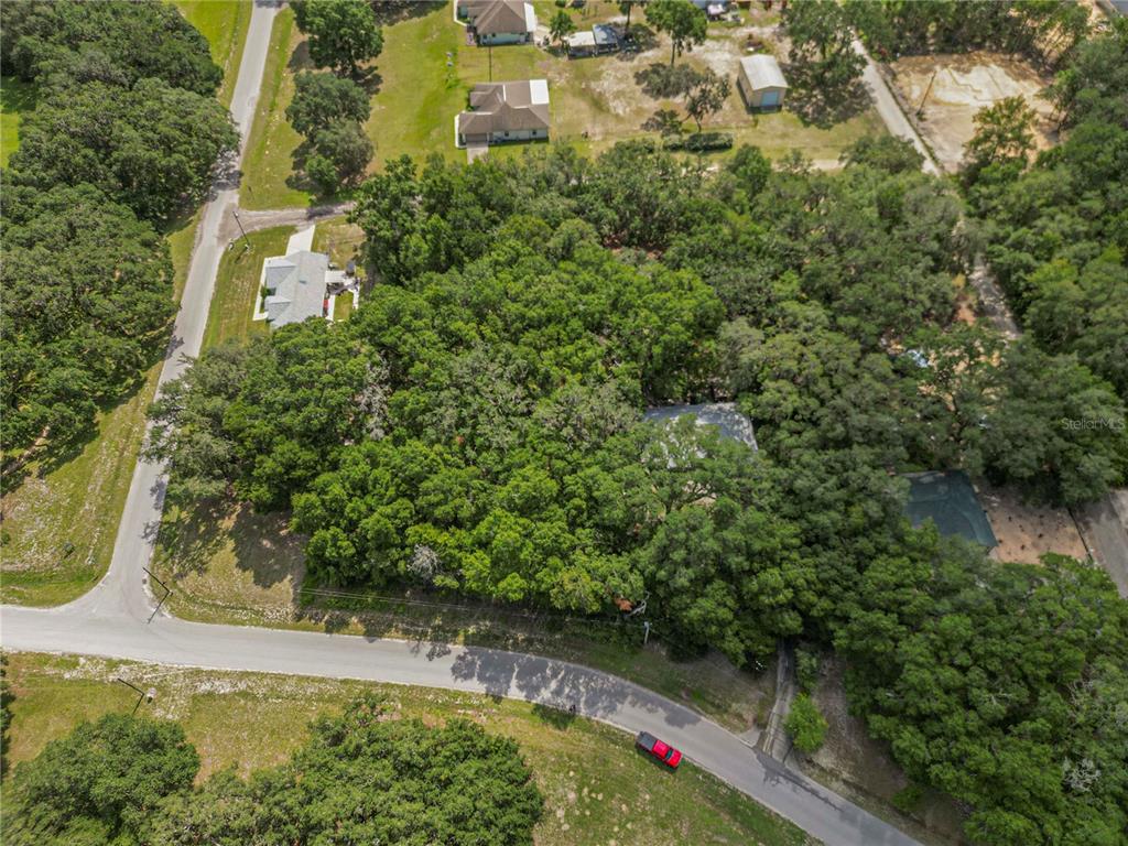 An aerial view shows a house nestled within a dense forest near a paved road — TBD SW 136TH COURT RD, DUNNELLON, FL
