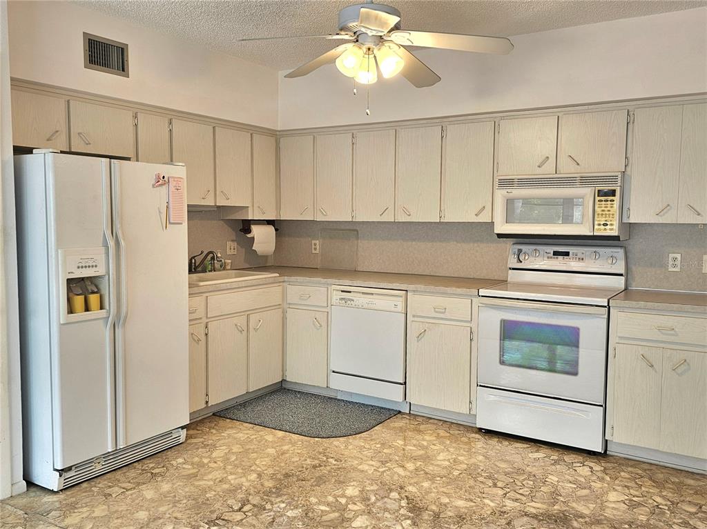 A kitchen with white appliances, light-colored cabinets, and patterned flooring — 2284 PHILIPPINE DRIVE UNIT 39, CLEARWATER, FL