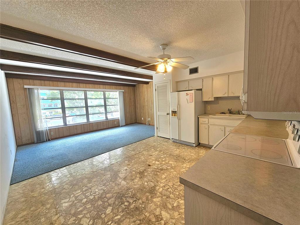 A kitchen with light cabinets and a dining area featuring wood-paneled walls and exposed beams — 2284 PHILIPPINE DRIVE UNIT 39, CLEARWATER, FL