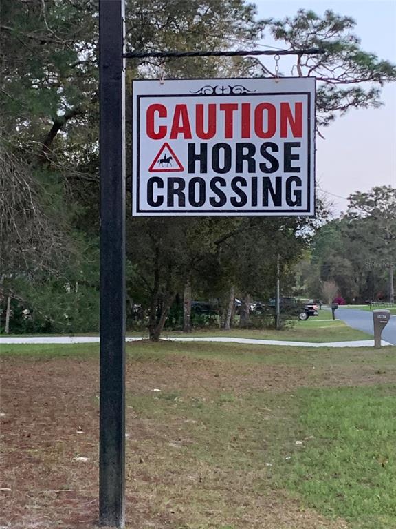 A sign reading "Caution Horse Crossing" hangs from a black metal post outdoors — 5202 N ALLAMANDRA DRIVE, BEVERLY HILLS, FL
