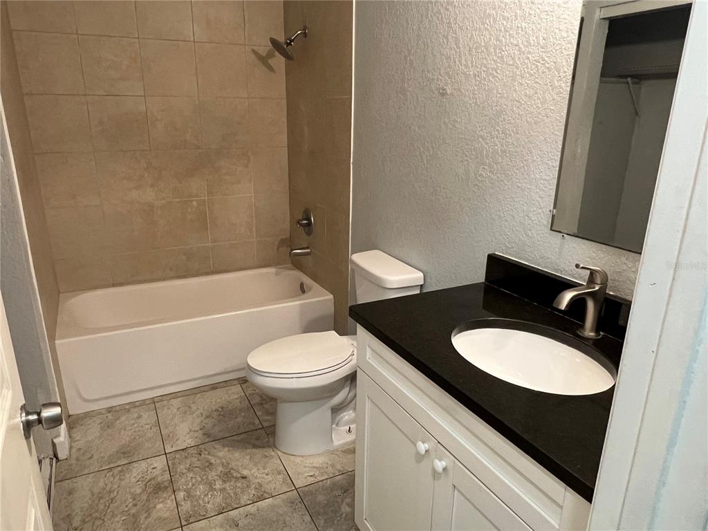A bathroom features a white vanity with a black countertop, a toilet, and a tiled tub — 920 MAYDELL DRIVE UNIT A, TAMPA, FL