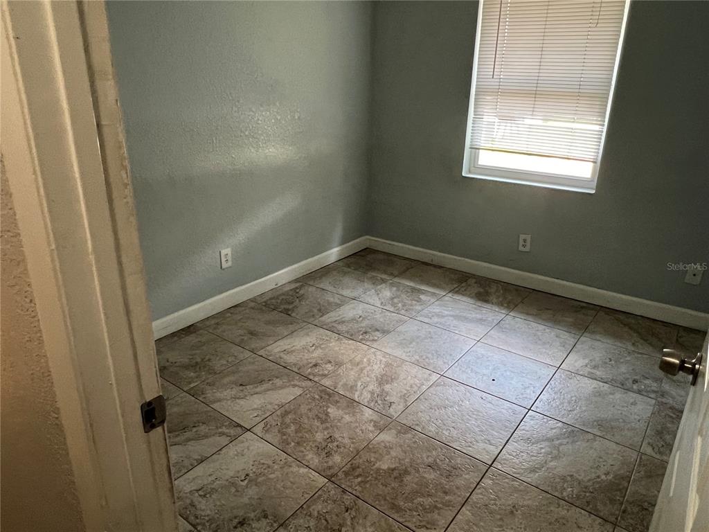 An empty room features light blue walls, white trim, and brown tiled flooring — 920 MAYDELL DRIVE UNIT A, TAMPA, FL
