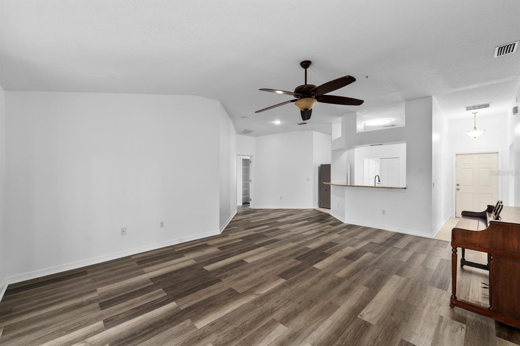 An open-concept living area features white walls, a ceiling fan, and wood-look plank flooring — 3609 TRAPNELL GROVE LOOP, PLANT CITY, FL