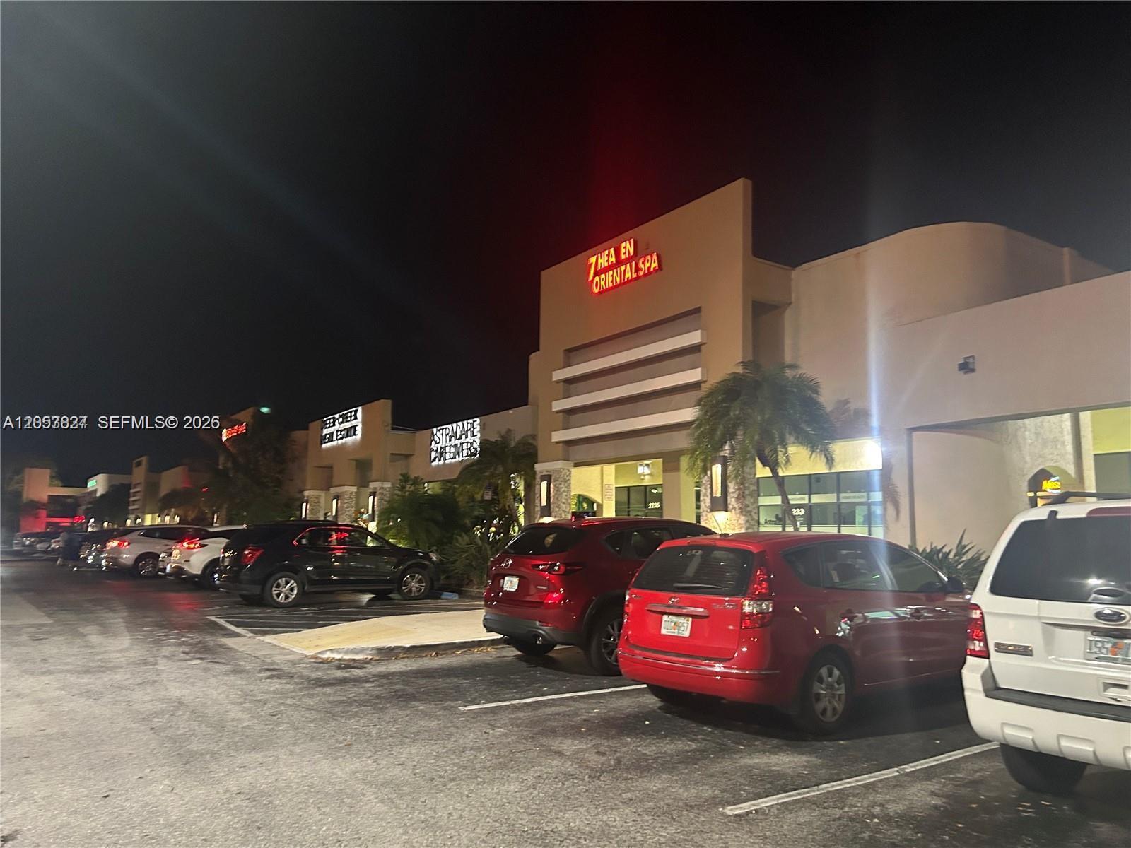 A parking lot sits in front of a commercial building at night with several cars — 2215 W Hillsboro Blvd # 01, Deerfield Beach FL 33442, DEERFIELD BEACH, FL