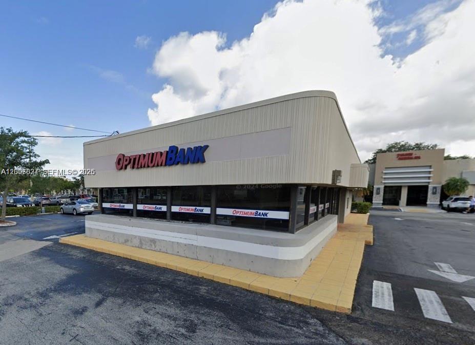The exterior of a single-story OptimumBank building features a flat roof and large glass windows — 2215 W Hillsboro Blvd # 01, Deerfield Beach FL 33442, DEERFIELD BEACH, FL