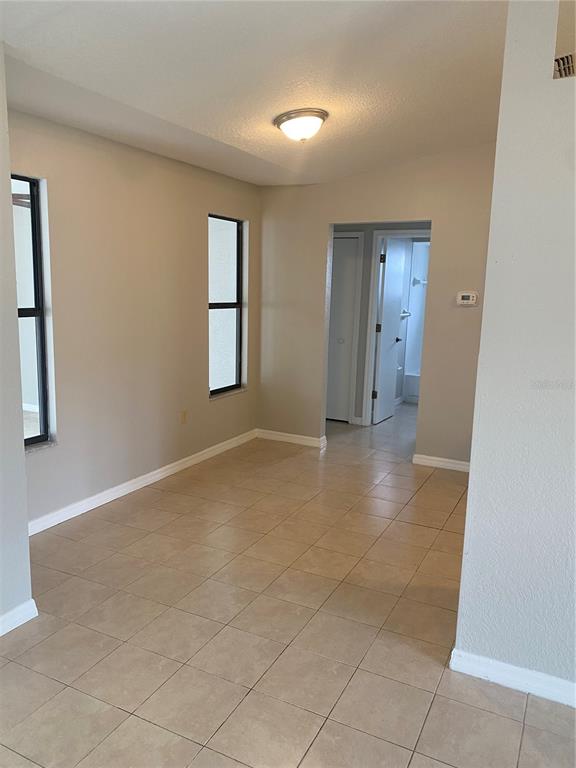 A room with beige walls, tile flooring, two windows, and a doorway leading to a bathroom — 2459 LANDOVER BOULEVARD, SPRING HILL, FL