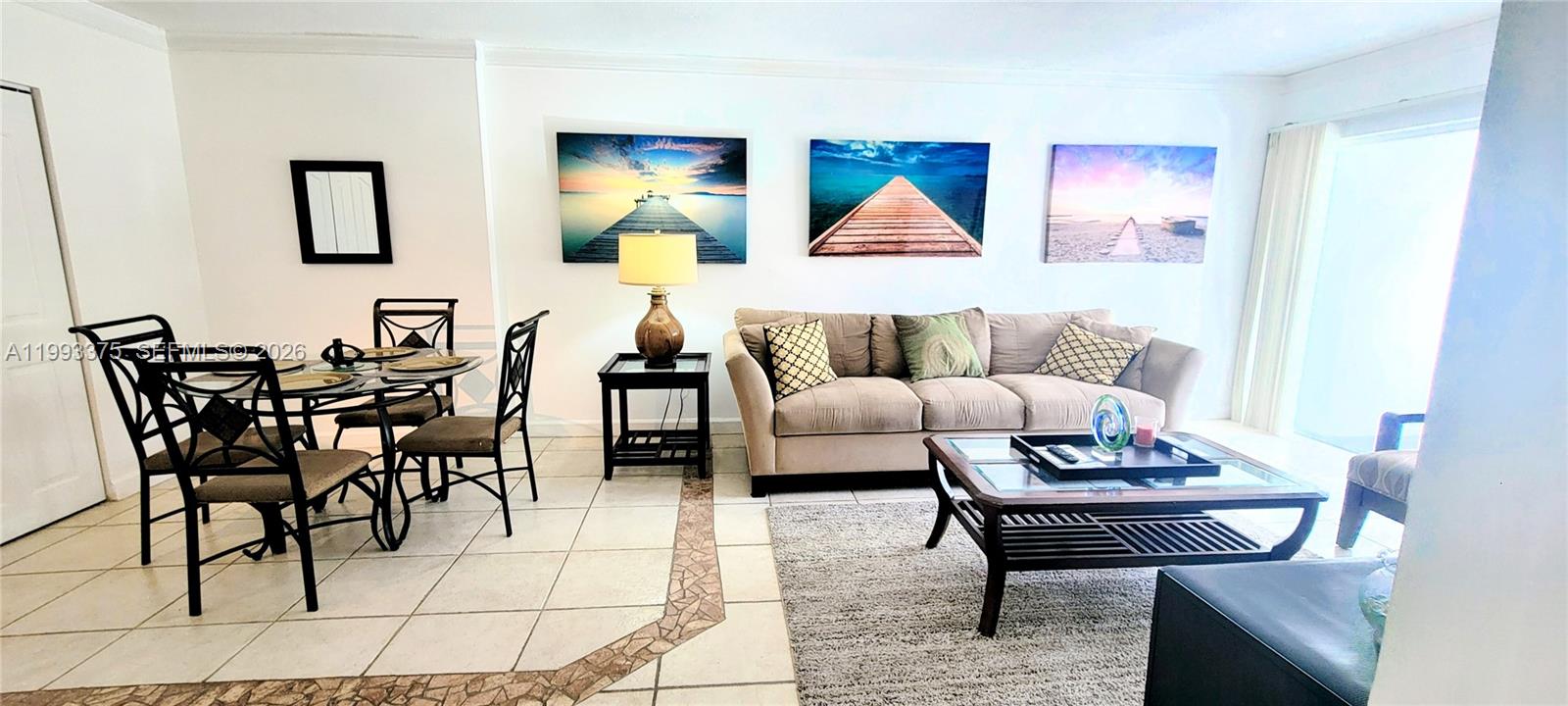 A living and dining area features tile flooring, a beige sofa, and three wall-mounted landscape prints — 400 S Kings Point Dr # 220, Sunny Isles Beach FL 33160, SUNNY ISLES BEACH, FL