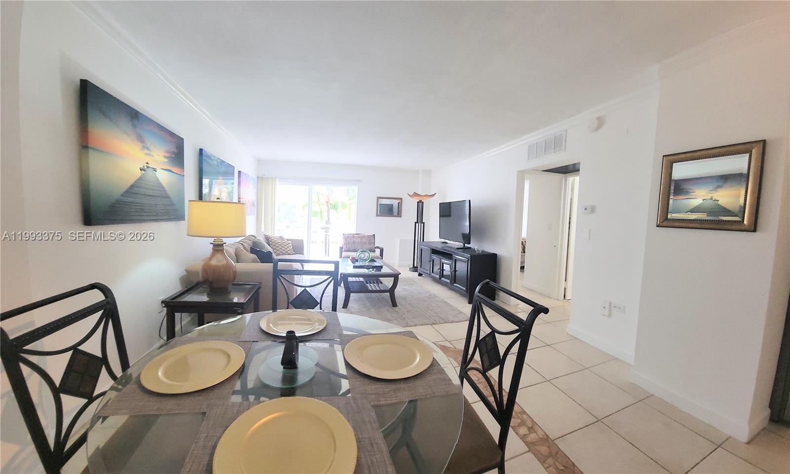A dining area with a glass table overlooks a living room featuring tile flooring — 400 S Kings Point Dr # 220, Sunny Isles Beach FL 33160, SUNNY ISLES BEACH, FL