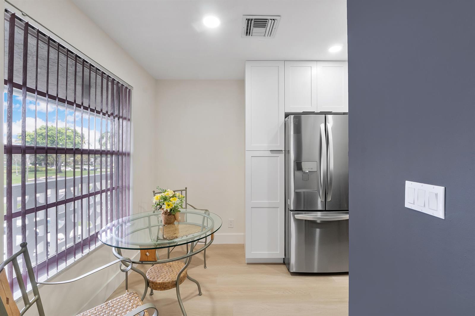 A dining nook features a glass table, wicker chairs, and a stainless steel refrigerator — 1030 Citrus Way # 204, Delray Beach FL 33445, DELRAY BEACH, FL