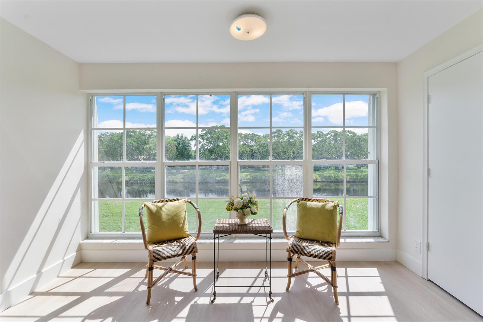 A sunlit room features two wicker chairs and a small table facing a large window — 1030 Citrus Way # 204, Delray Beach FL 33445, DELRAY BEACH, FL