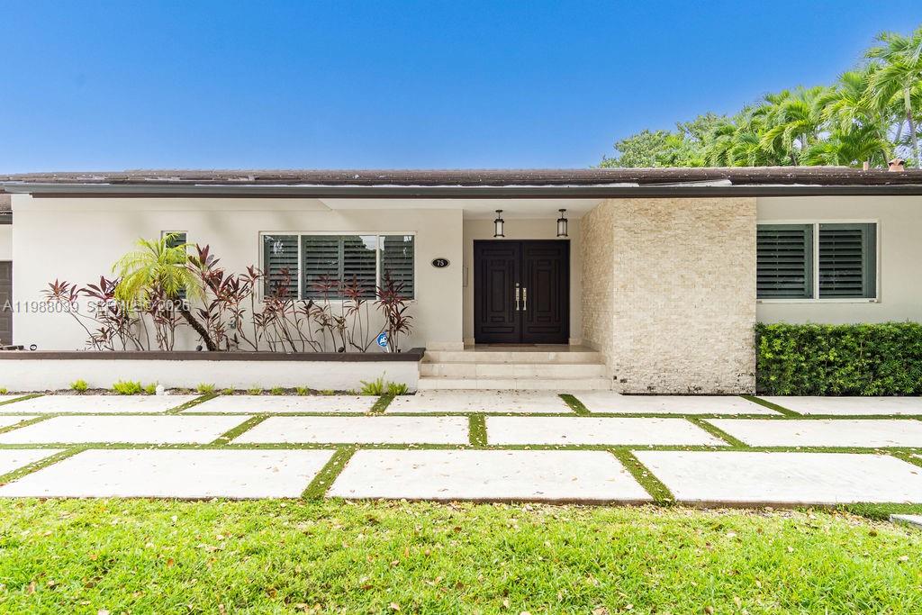 A single-story house with a white exterior, stone accent wall, and a paved driveway — 75 S Prospect Dr, Coral Gables FL 33133, CORAL GABLES, FL